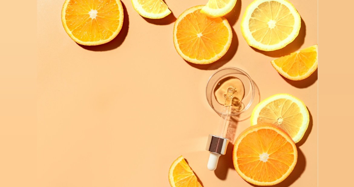 Sérum facial em fundo laranja ao redor de fatias da fruta laranja.